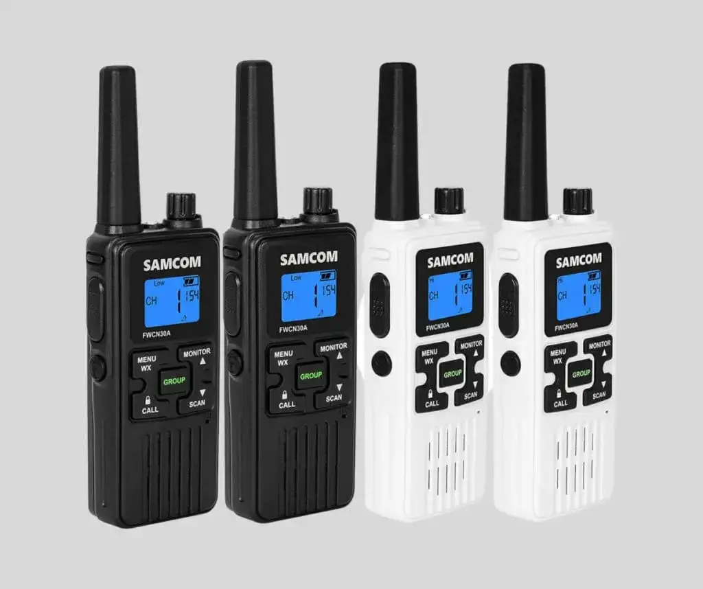 Four SAMCOM walkie-talkies, two black and two white, with digital displays, antennas, and labeled buttons including MENU, MONITOR, WX, GROUP, CALL, and SCAN, set against a gray background